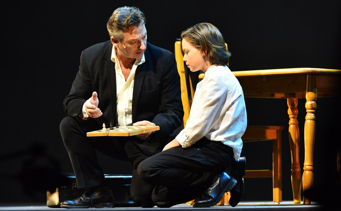 Anders i rollen som Anatolij sitter på huk och berättar om schack för sin son. 
